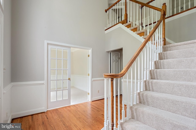 stairs with hardwood / wood-style floors and a high ceiling