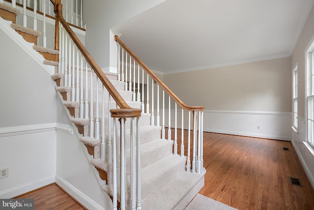 stairs featuring ornamental molding and hardwood / wood-style floors