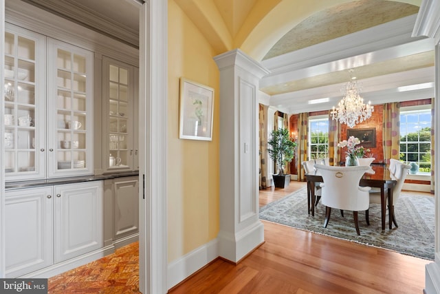 dining space featuring light wood-type flooring, crown molding, a chandelier, and a healthy amount of sunlight