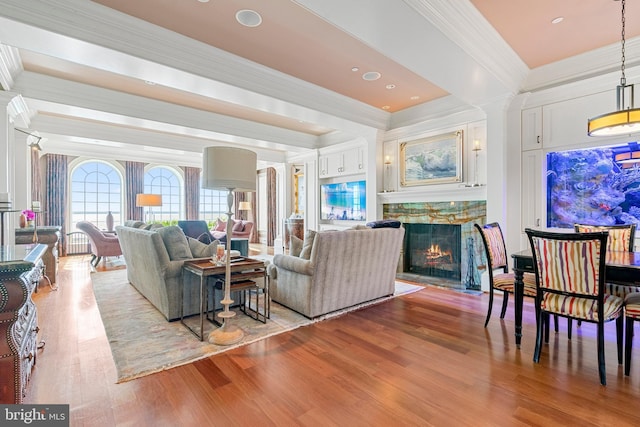 living room with light wood-type flooring, ornamental molding, and a fireplace