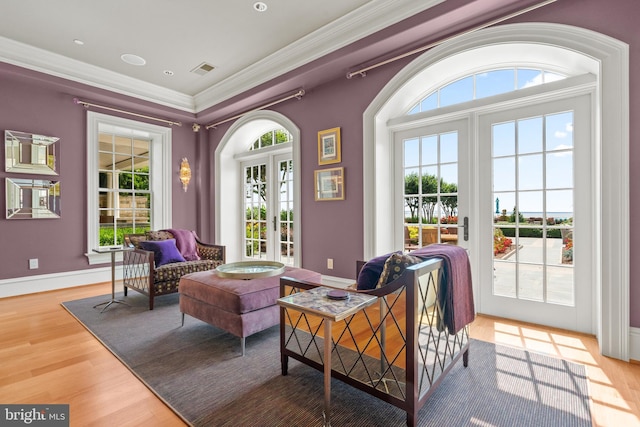 sitting room with plenty of natural light, ornamental molding, light hardwood / wood-style floors, and french doors