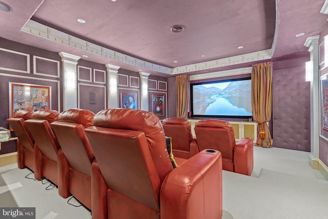 carpeted home theater room featuring a tray ceiling and decorative columns