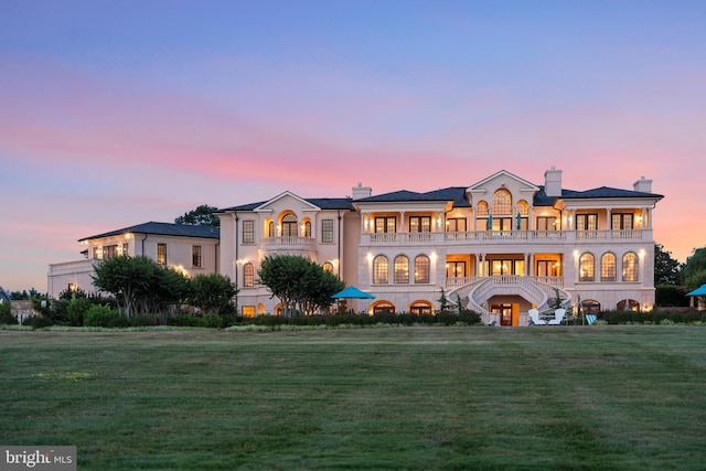 view of front of home featuring a balcony and a yard