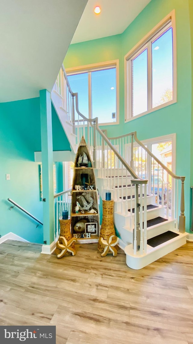 staircase with wood-type flooring and a towering ceiling