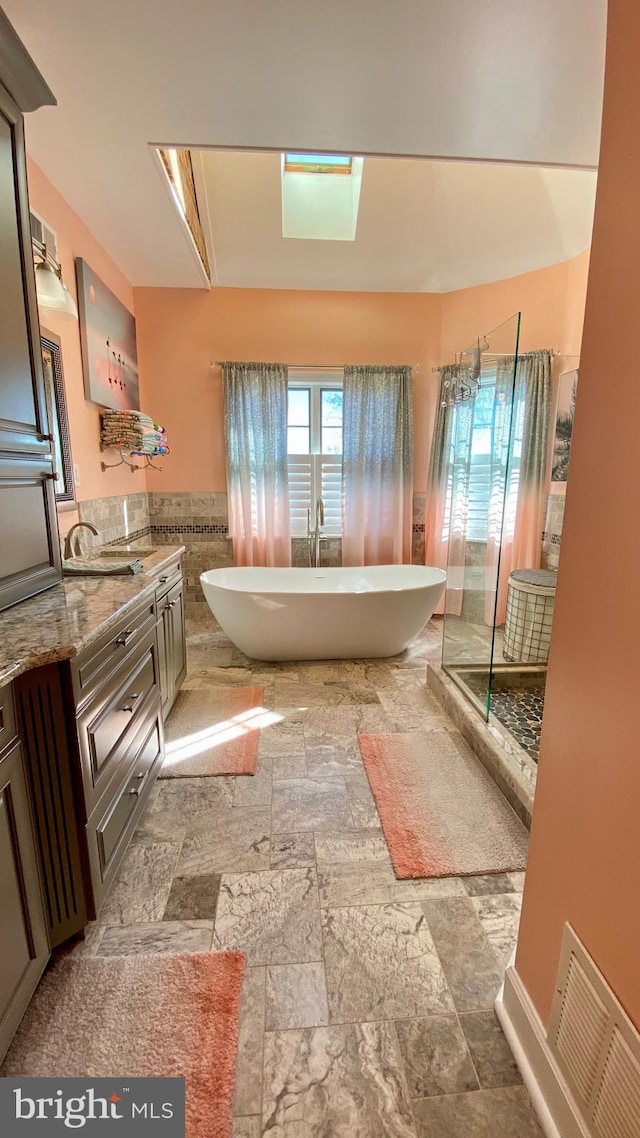 bathroom with a tub to relax in, vanity, and tile walls