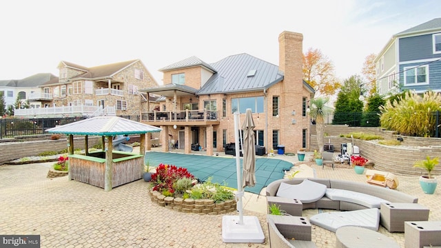 rear view of property featuring a balcony, a covered pool, and a patio area