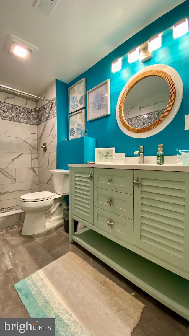 bathroom featuring toilet, vanity, and tiled shower