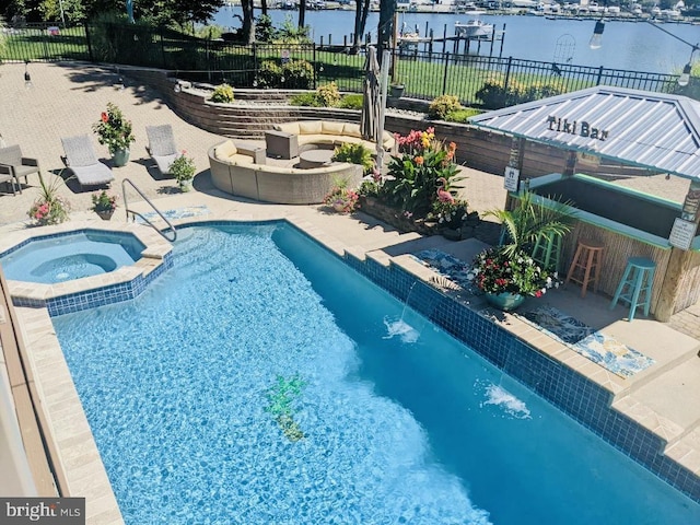 view of pool featuring a patio, a water view, and an in ground hot tub