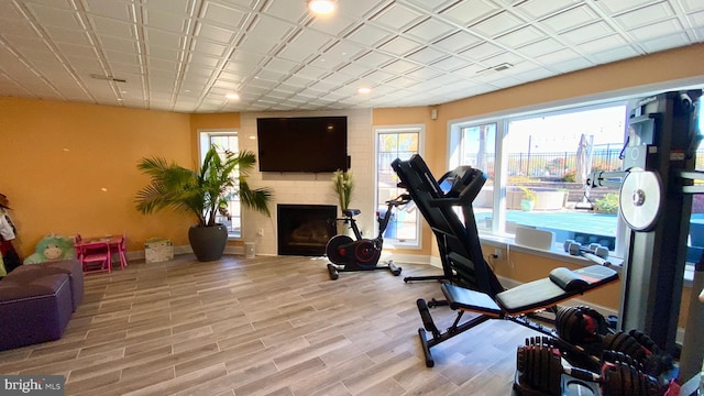 workout room with a large fireplace and light wood-type flooring