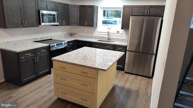 kitchen featuring a kitchen island, sink, appliances with stainless steel finishes, and light hardwood / wood-style flooring