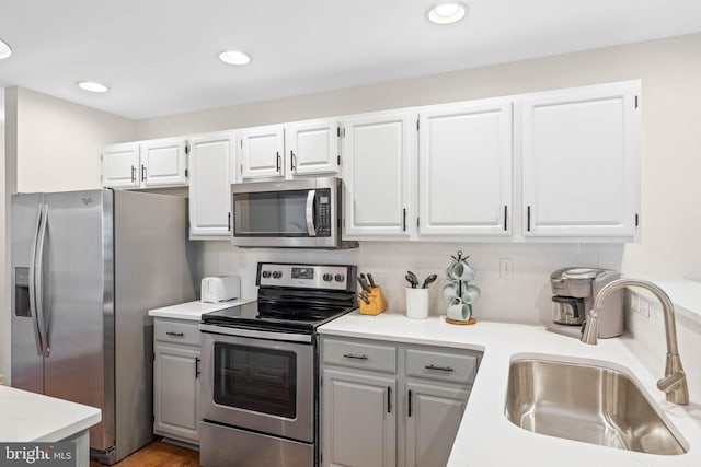 kitchen featuring wood-type flooring, white cabinets, decorative backsplash, sink, and appliances with stainless steel finishes