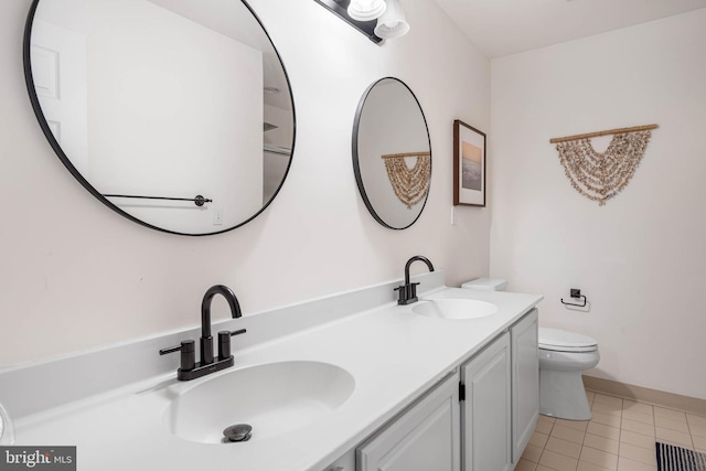 bathroom with toilet, vanity, and tile patterned flooring