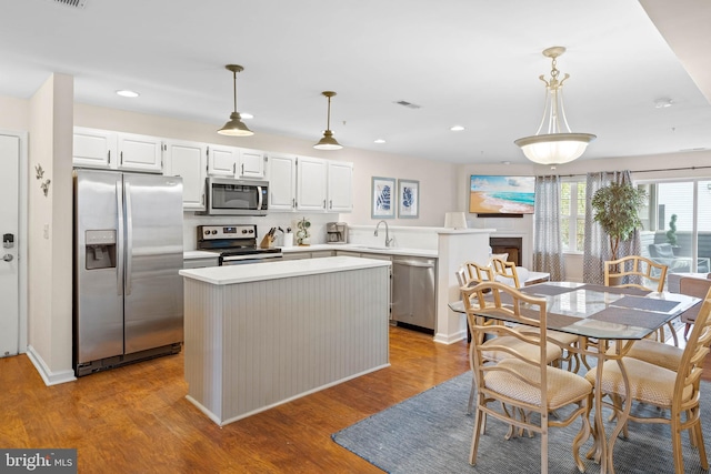 kitchen with white cabinetry, pendant lighting, light hardwood / wood-style floors, and stainless steel appliances