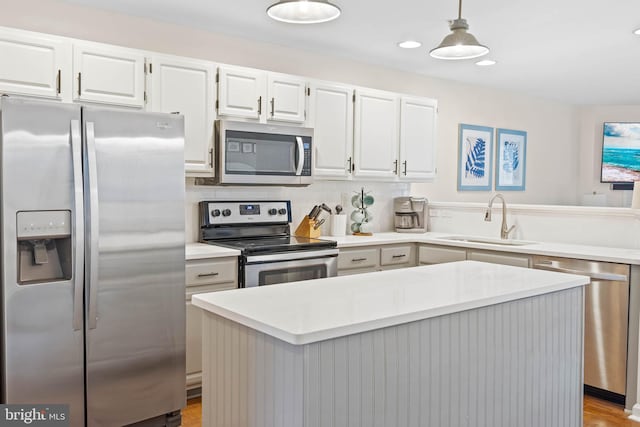 kitchen featuring stainless steel appliances, a center island, white cabinets, hanging light fixtures, and sink