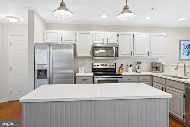 kitchen featuring stainless steel appliances, white cabinetry, sink, and decorative light fixtures