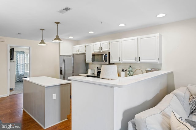 kitchen featuring stainless steel appliances, white cabinetry, dark hardwood / wood-style floors, hanging light fixtures, and kitchen peninsula