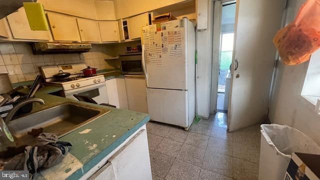 kitchen featuring white appliances, ventilation hood, sink, and backsplash