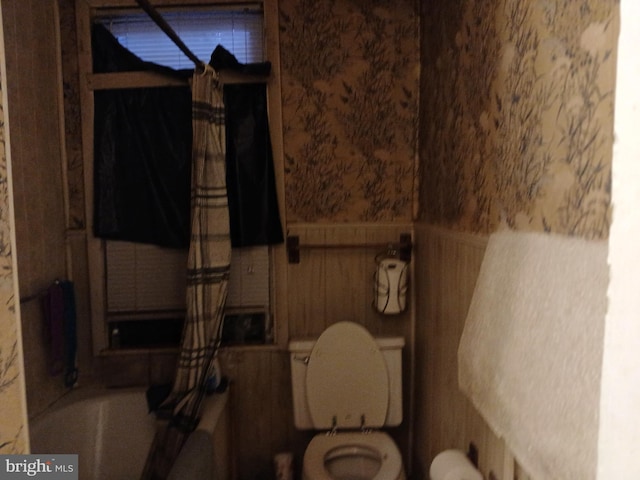 full bathroom with a washtub, wainscoting, toilet, and wallpapered walls