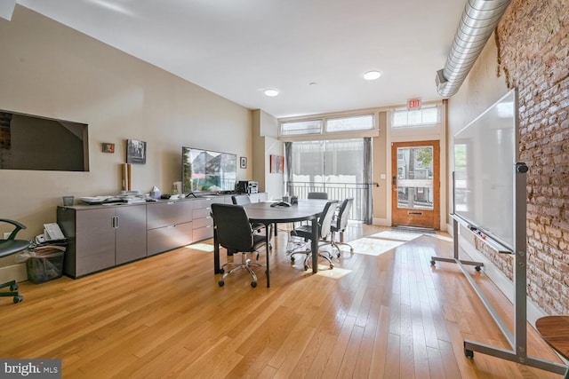 dining room featuring light wood-type flooring and a towering ceiling