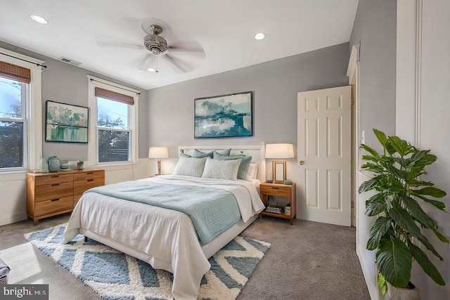 bedroom featuring ceiling fan, multiple windows, and light carpet