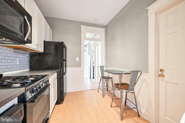 kitchen with light hardwood / wood-style flooring, decorative backsplash, gas range, and white cabinets