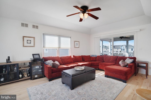 living room featuring light hardwood / wood-style floors, vaulted ceiling, and ceiling fan