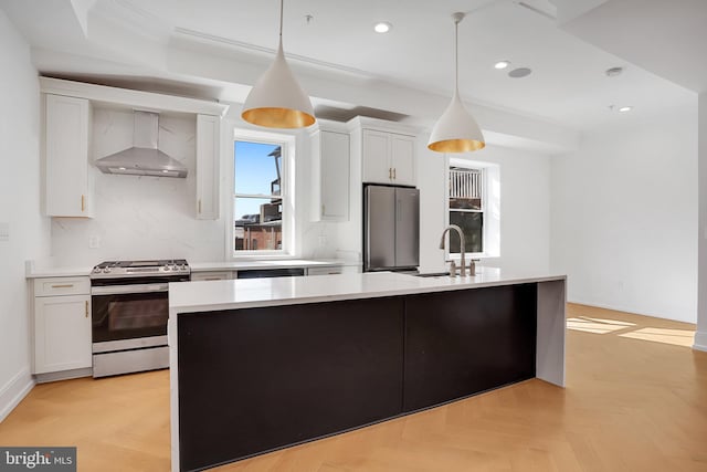 kitchen featuring stainless steel appliances, pendant lighting, white cabinets, wall chimney range hood, and light parquet flooring