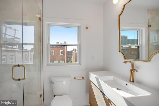 bathroom featuring toilet, vanity, and a shower with door