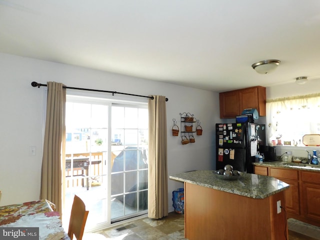 kitchen with a kitchen island, black fridge, a wealth of natural light, and sink