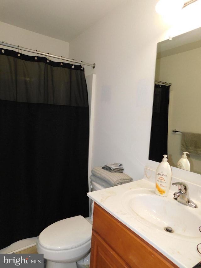 bathroom with curtained shower, vanity, and toilet