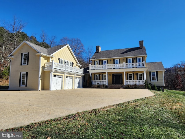 colonial-style house with a garage, a front yard, a balcony, and a porch