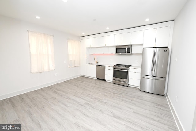 kitchen featuring stainless steel appliances, light hardwood / wood-style floors, white cabinets, and sink