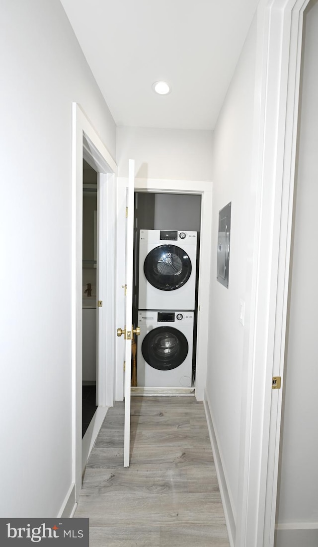 washroom with light hardwood / wood-style floors and stacked washer / drying machine