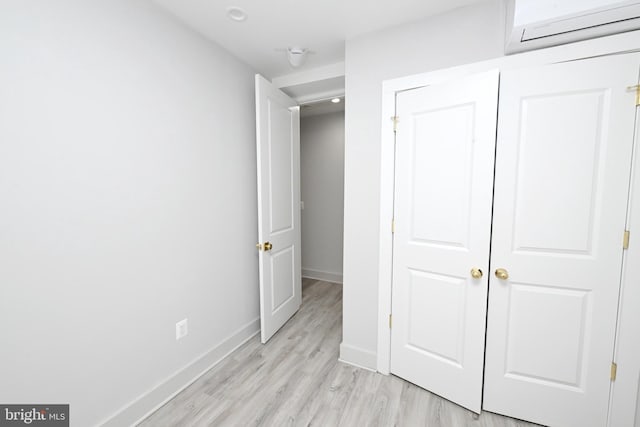 unfurnished bedroom with a closet, light hardwood / wood-style flooring, and a wall mounted air conditioner