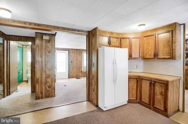 kitchen featuring wood walls, light carpet, and white fridge