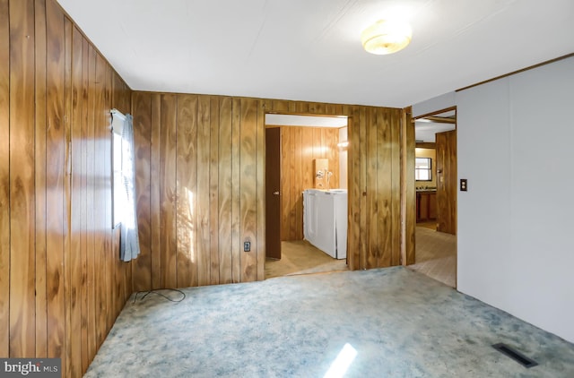 spare room with light colored carpet and wood walls