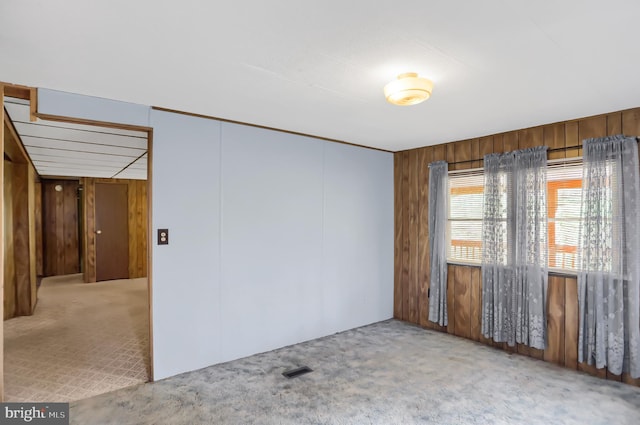 empty room featuring carpet flooring and wooden walls