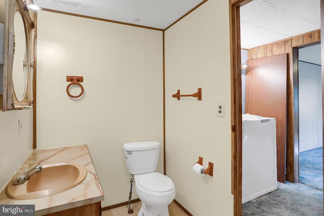 bathroom featuring ornamental molding, vanity, wooden walls, and toilet