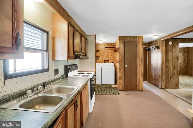 kitchen featuring white electric range oven, washing machine and dryer, wooden walls, and sink