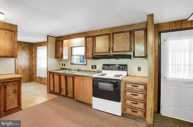 kitchen featuring white range with electric stovetop, wooden walls, and sink