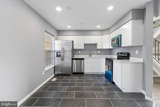 kitchen featuring white cabinets, dark tile patterned flooring, stainless steel appliances, and sink