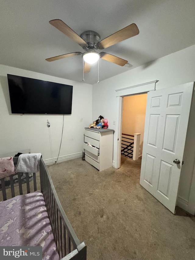 carpeted bedroom with a nursery area and ceiling fan