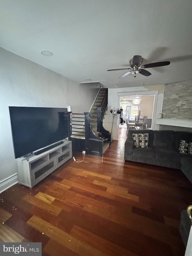 unfurnished living room with ceiling fan, dark hardwood / wood-style floors, and a large fireplace