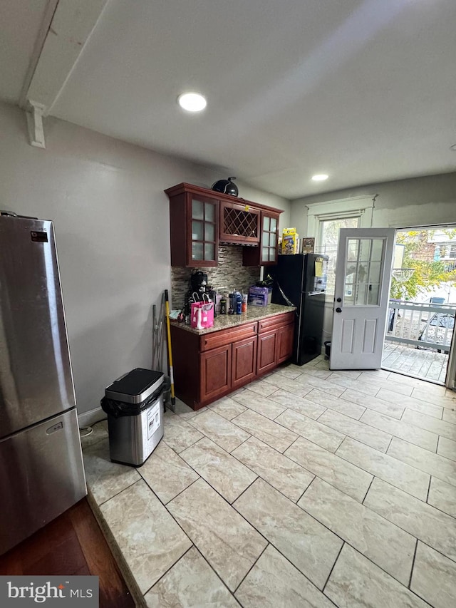 kitchen featuring stainless steel fridge, black fridge, and decorative backsplash