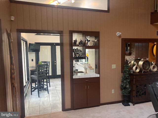 interior space featuring tile counters, wooden walls, and dark brown cabinets