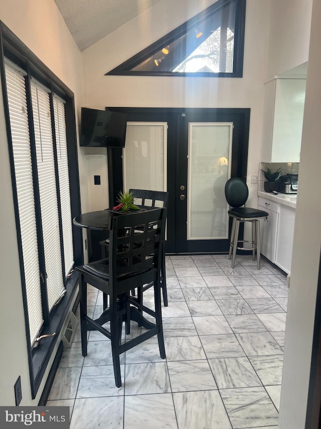 dining room featuring french doors, lofted ceiling, and a textured ceiling