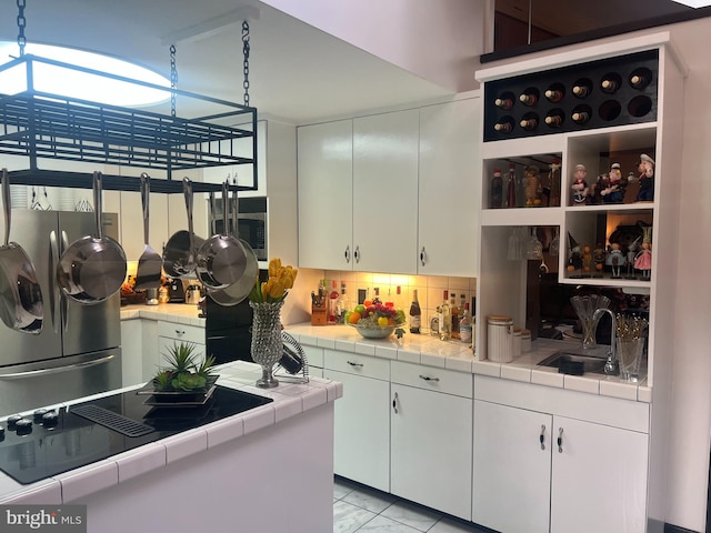 kitchen with tile countertops, decorative backsplash, white cabinetry, and sink