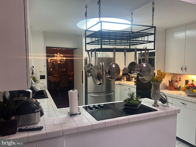 kitchen featuring tile countertops, appliances with stainless steel finishes, a chandelier, and white cabinets