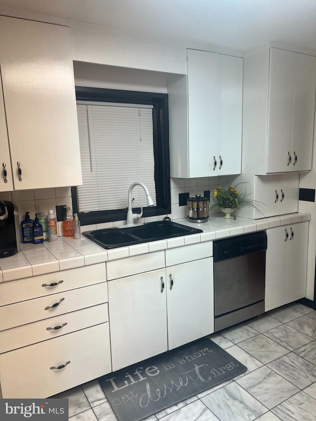 kitchen featuring stainless steel dishwasher, white cabinetry, sink, and backsplash