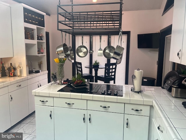 kitchen with sink, white cabinetry, cooktop, and tile counters